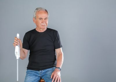 Elderly man sitting with the WeWALK cane in his right hand
